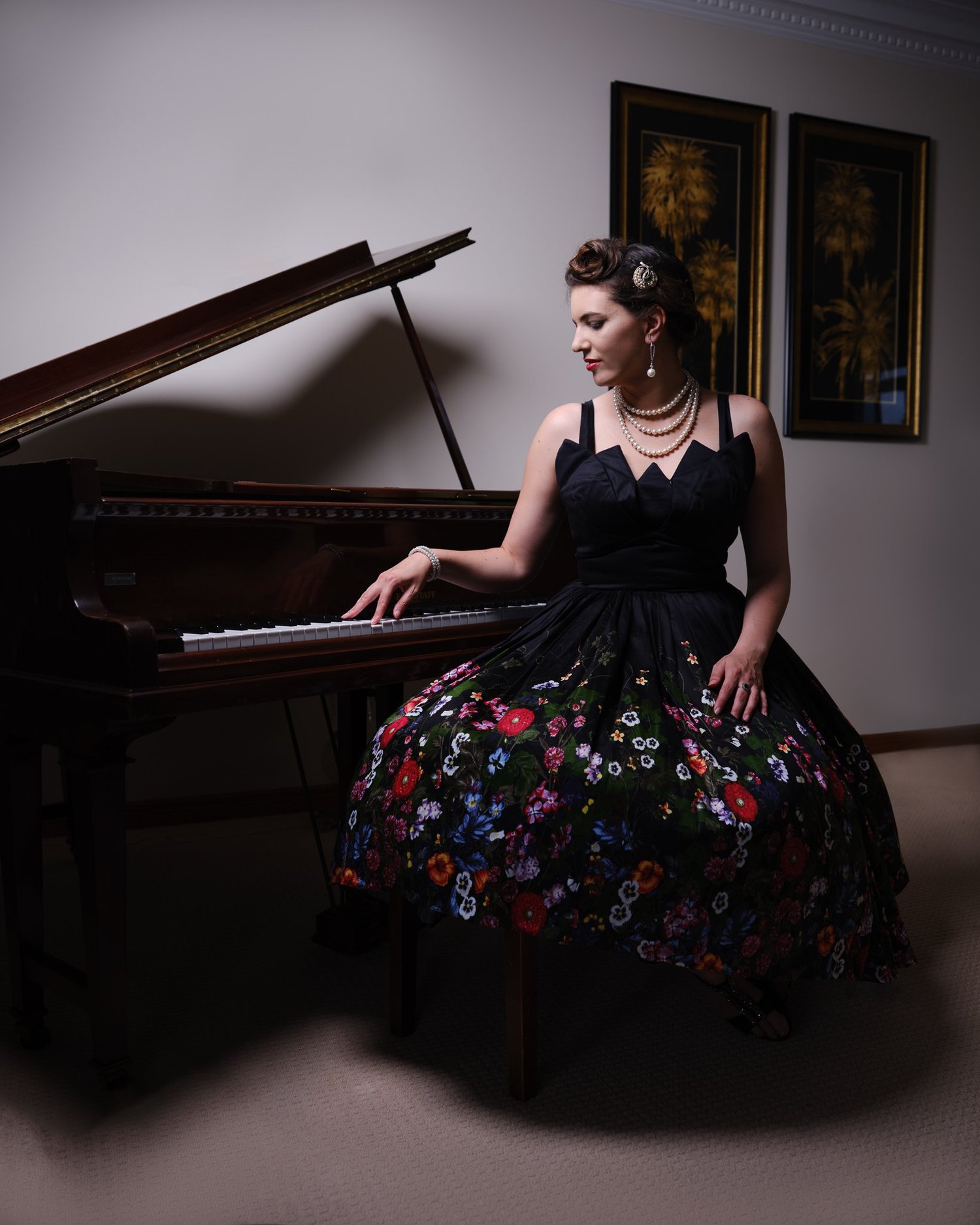 Jay seated at the piano in a floral skirt