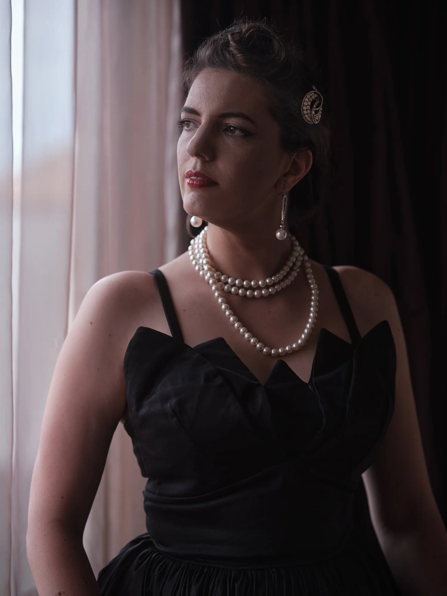 Jay in pearls looking out of a window