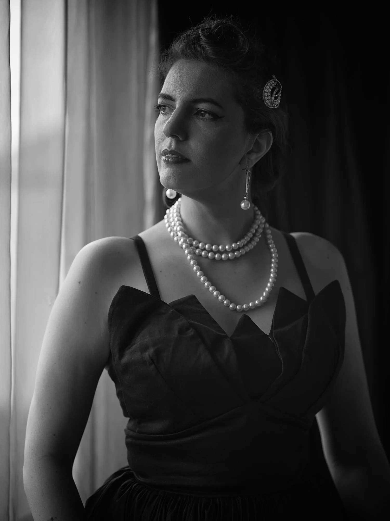 Black and white photo of Jay in pearls by the window