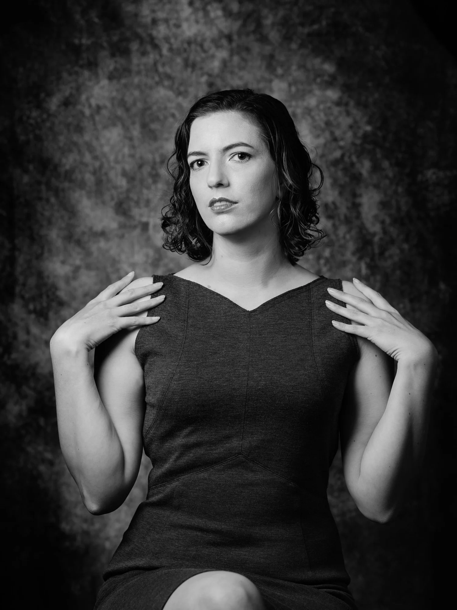 Black and white photo of Jay with hands on her shoulders against a painted backdrop