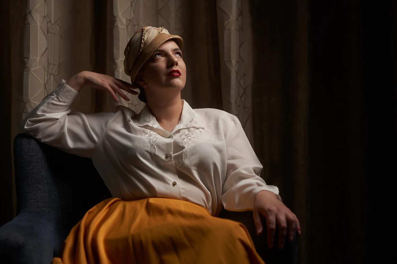 Jay in a white blouse and mustard skirt with a vintage hat