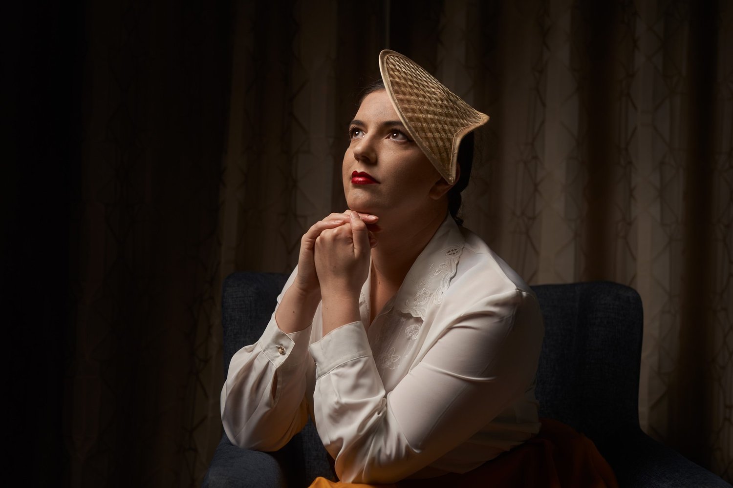Jay in a vintage hat with hands clasped looking upwards