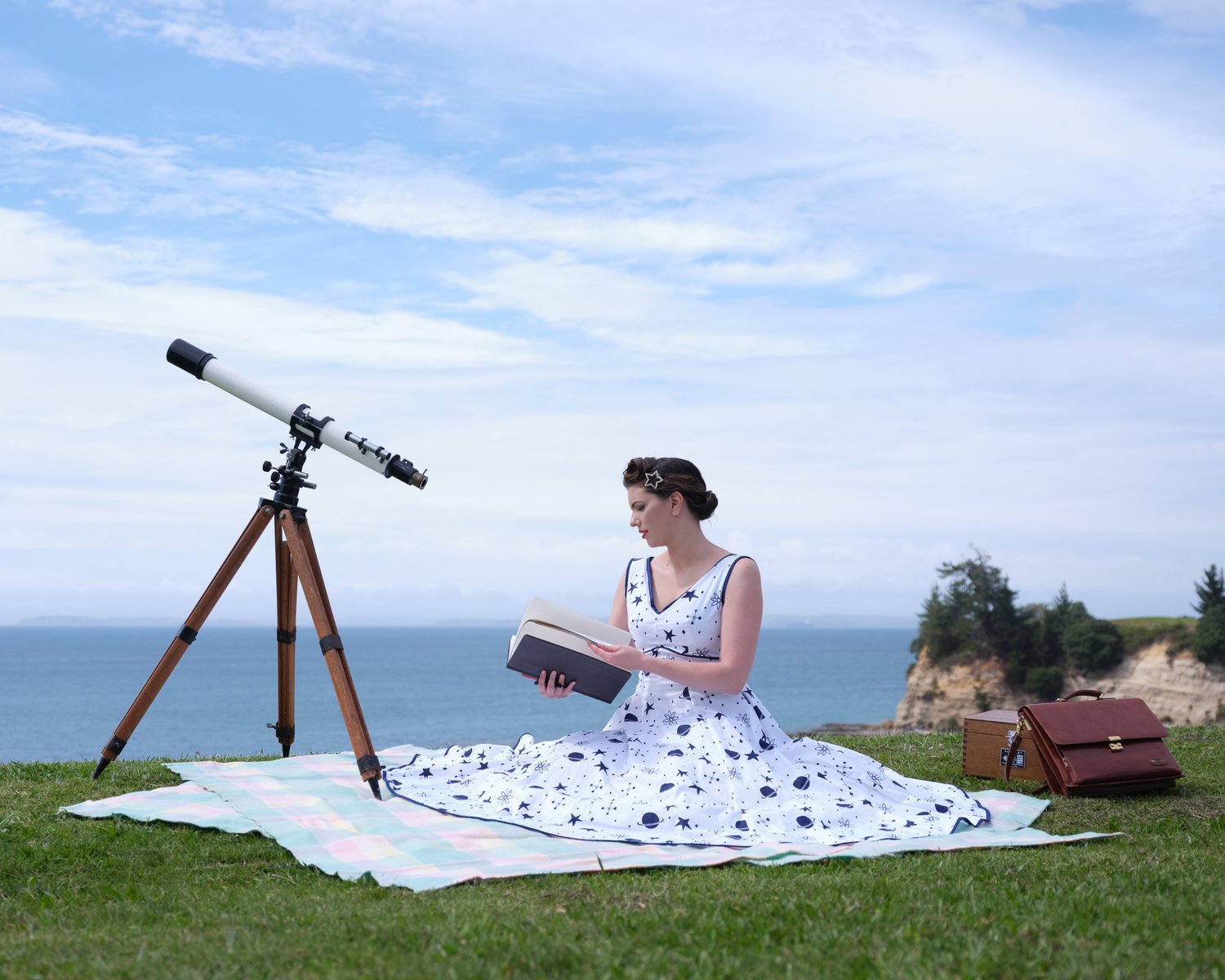 Jay with a book in a polka dot dress on a clifftop