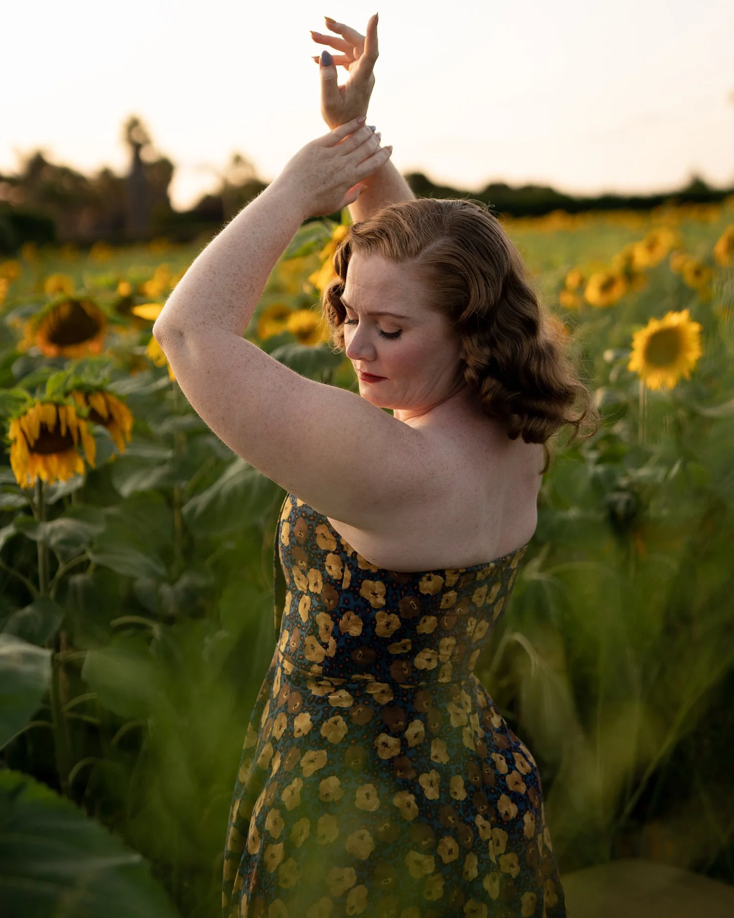 A model with arms raised in a sunflower print dress