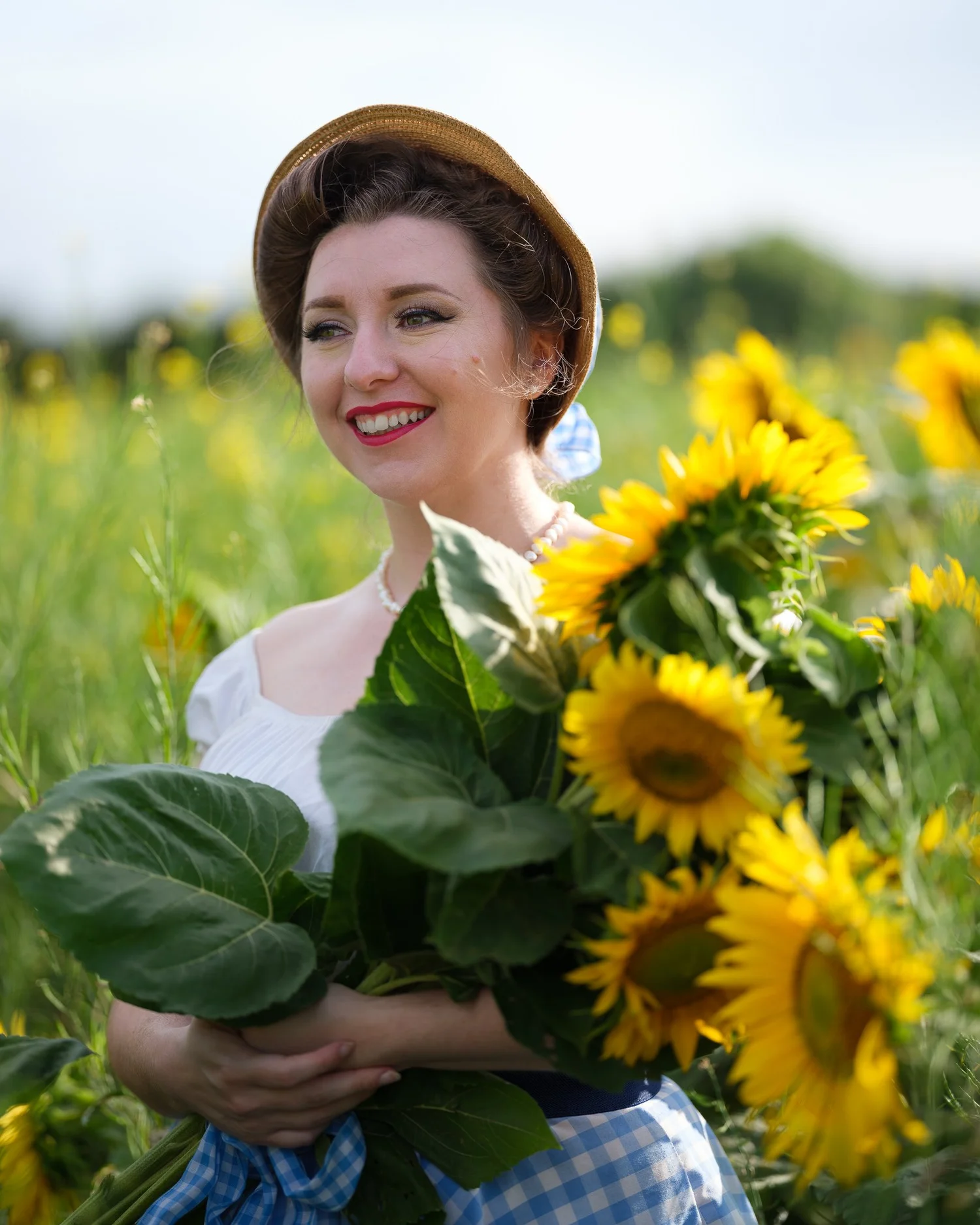 A smiling model holding an armful of sunflowers