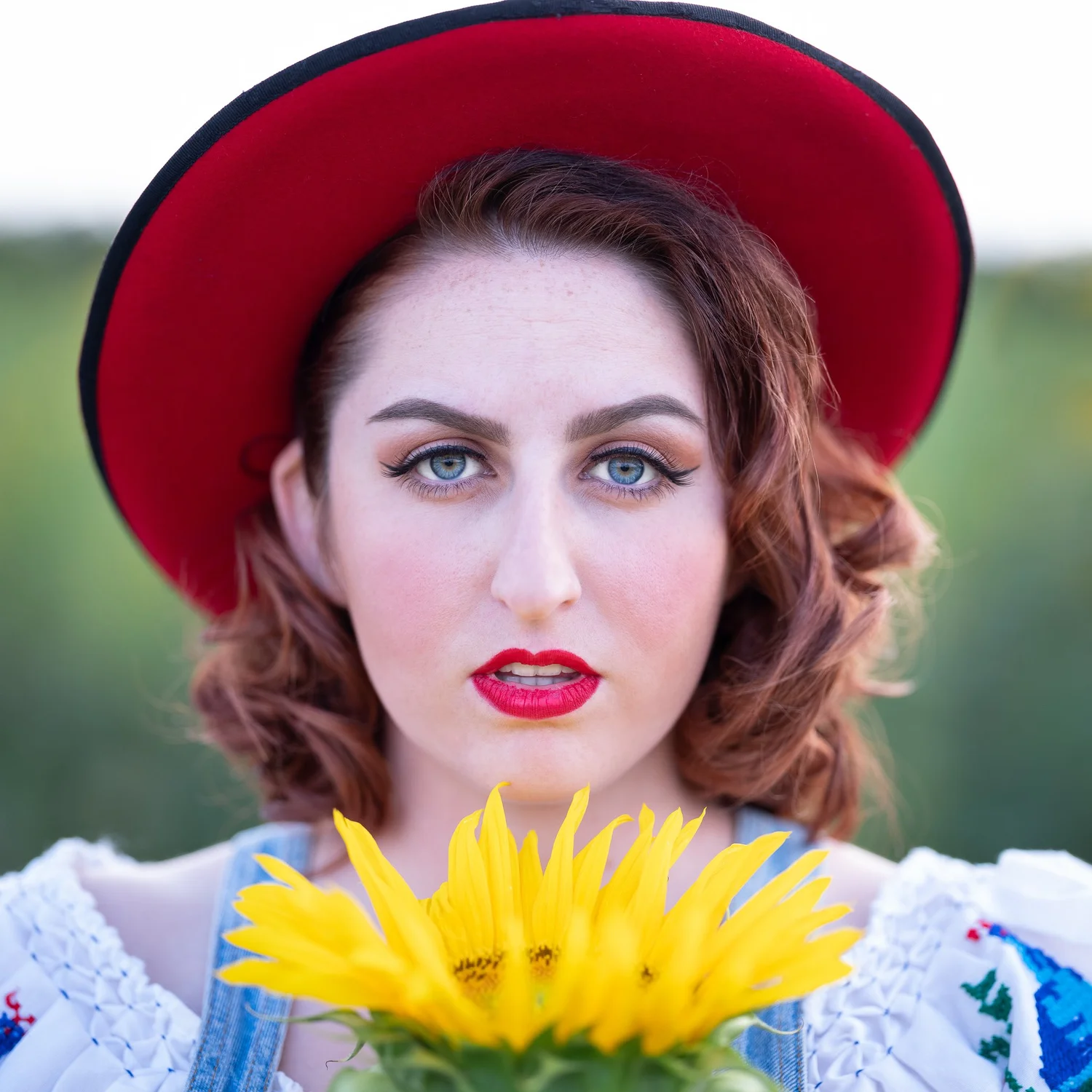 A model in a red hat holding a sunflower