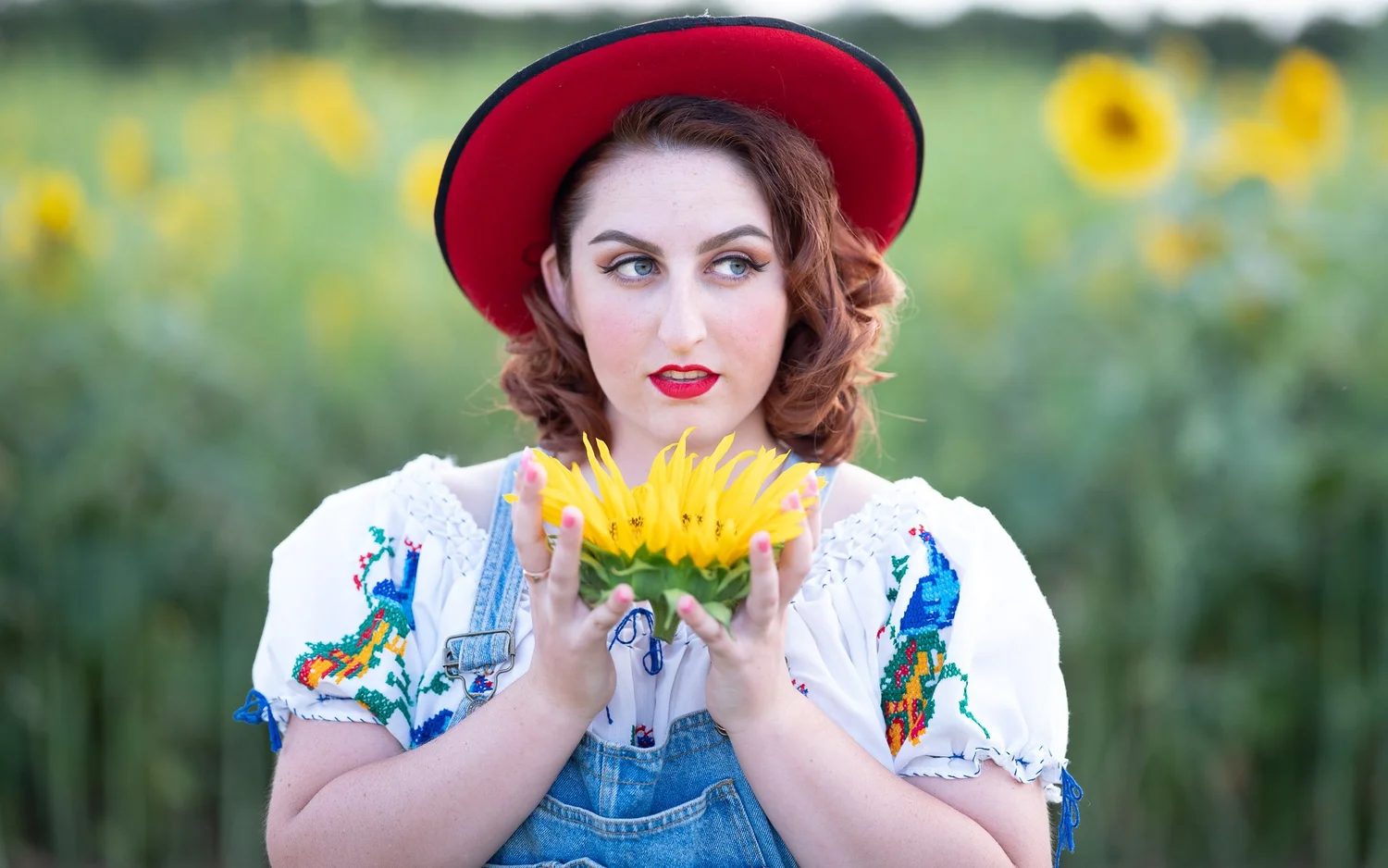 A model in a red hat holding sunflowers