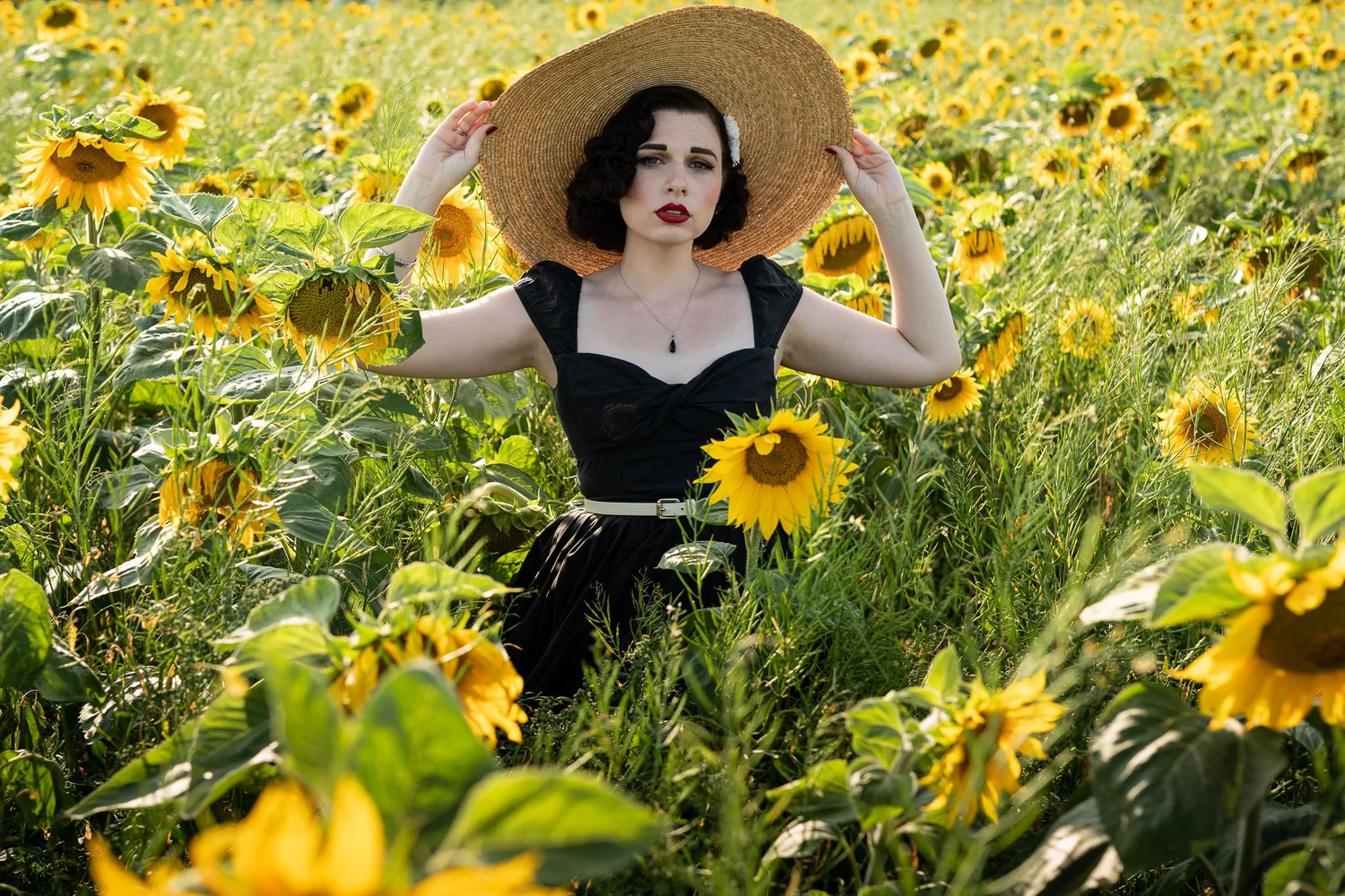 A model in a wide straw hat among the sunflowers