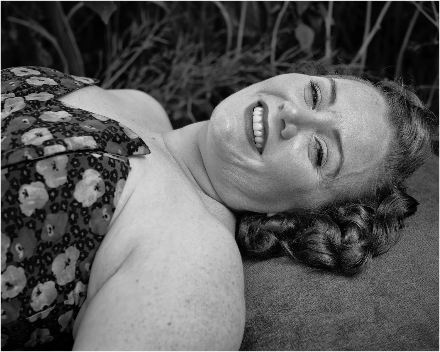 Black and white photo of a model lying back and laughing