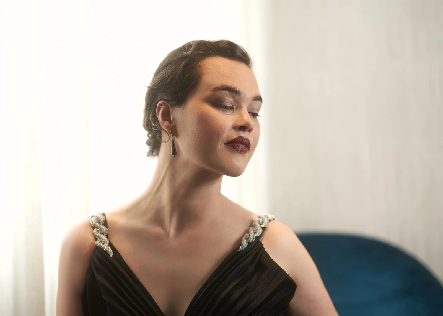 Anita in a black gown with eyes closed in soft window light