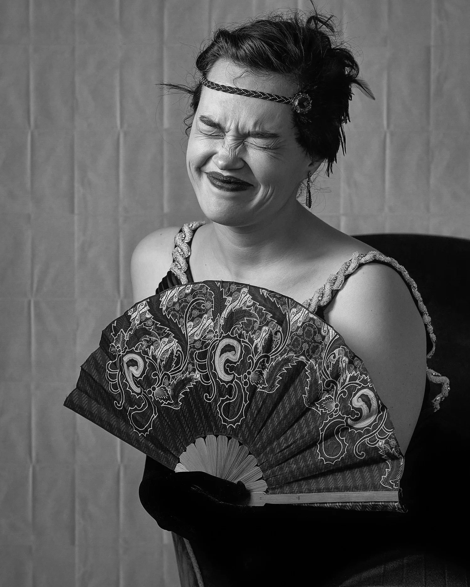 Black and white photo of Anita laughing behind a lace fan