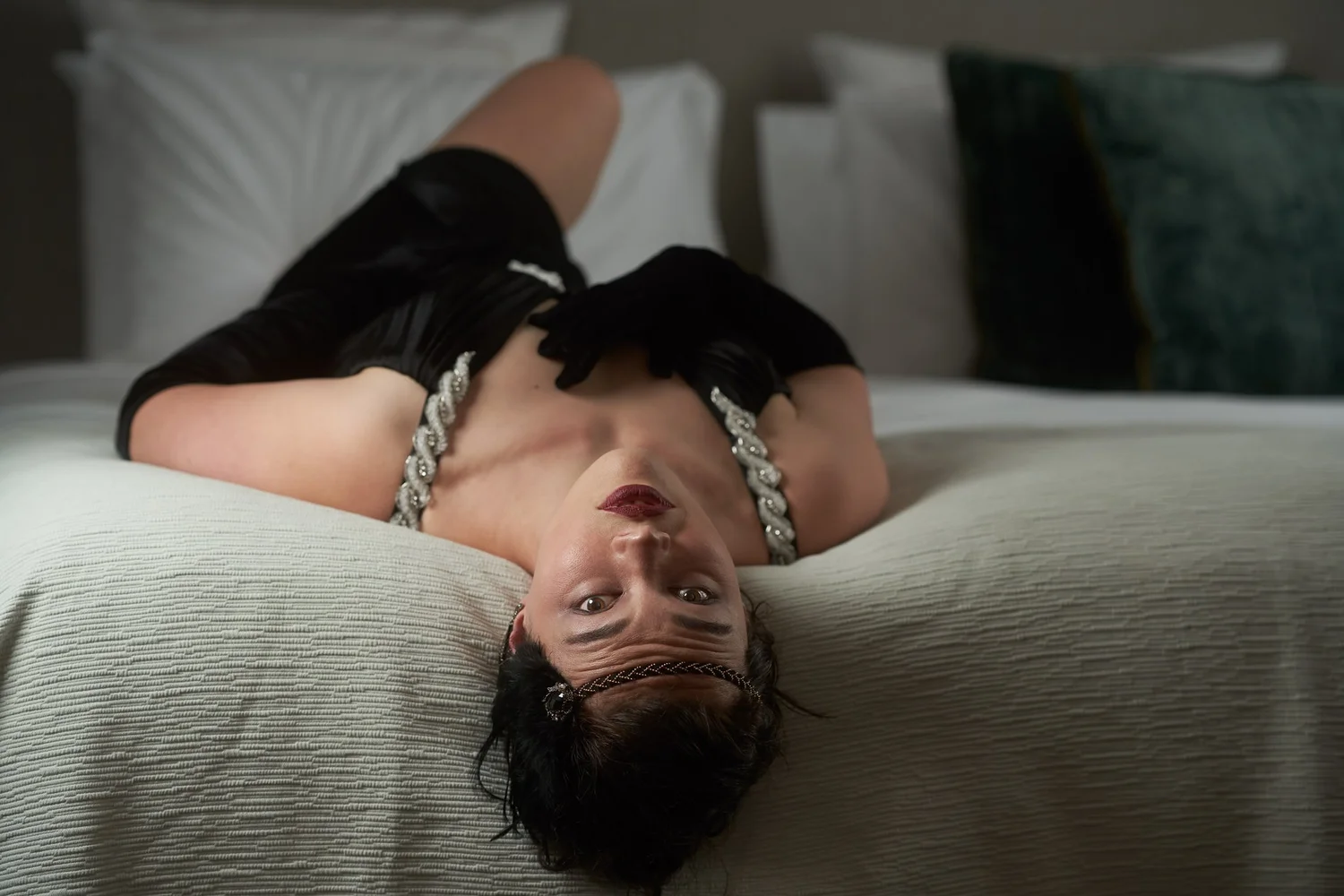 Anita lying back on a bed with her head tilted towards the camera