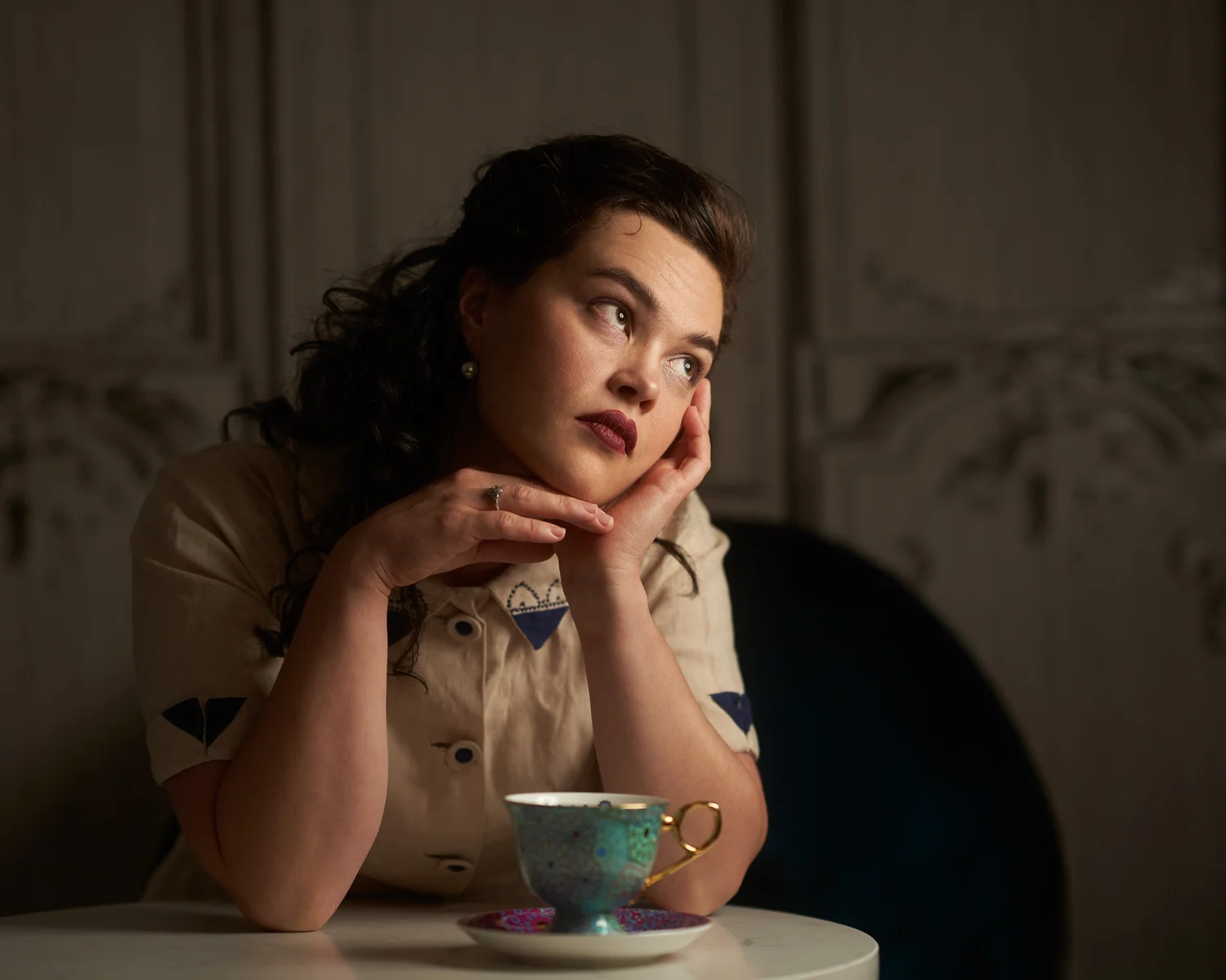 Anita rests her chin on her hands beside a teacup