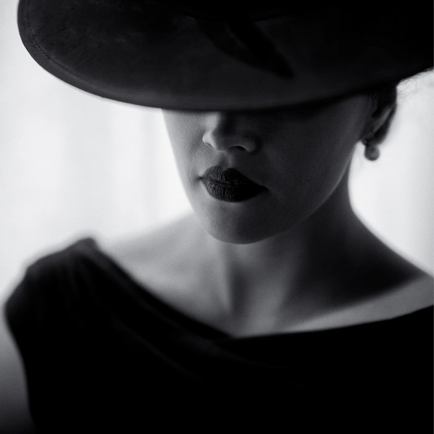 Black and white close-up of Anita's red lips beneath a wide-brimmed hat