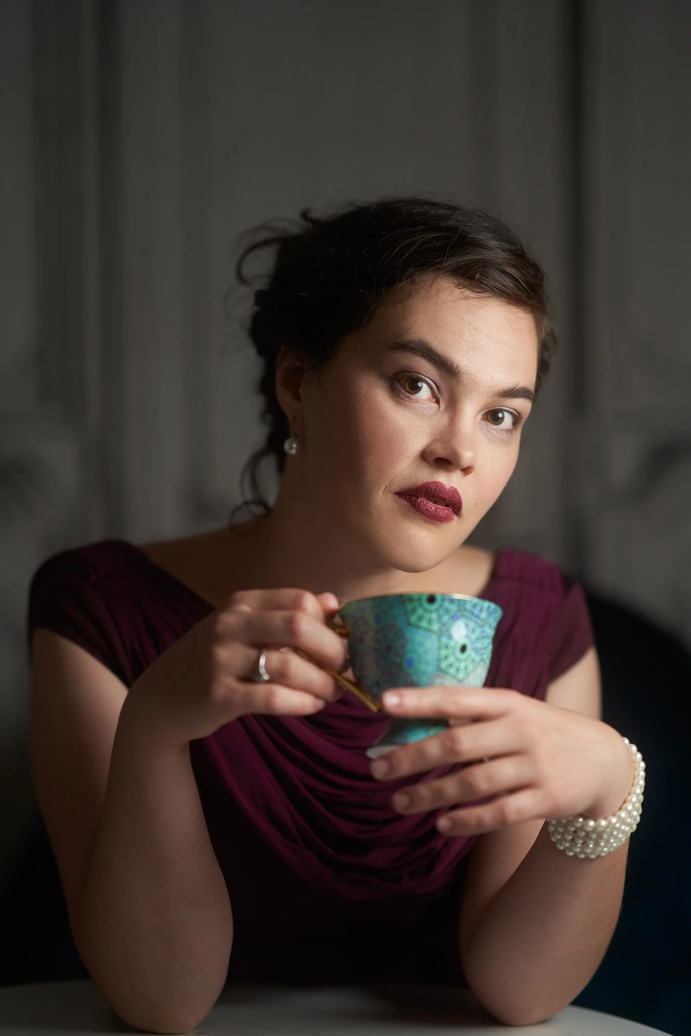 Anita in burgundy cradling a turquoise teacup
