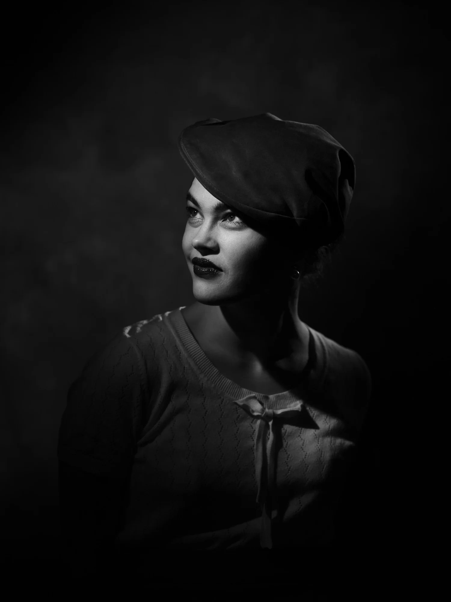 Black and white portrait of Anita in a beret, half in shadow