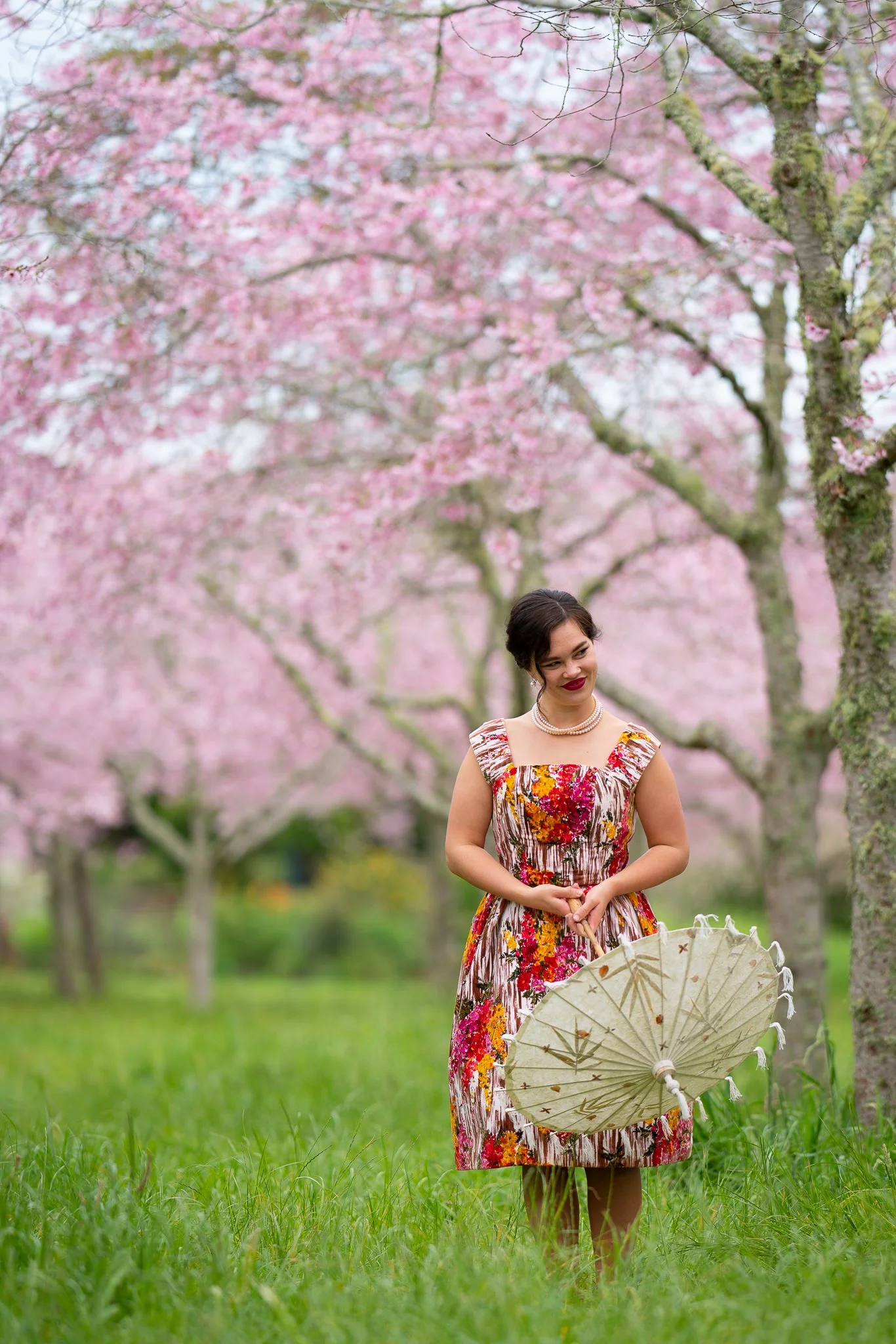 Anita with a lace parasol beneath pink cherry blossom trees