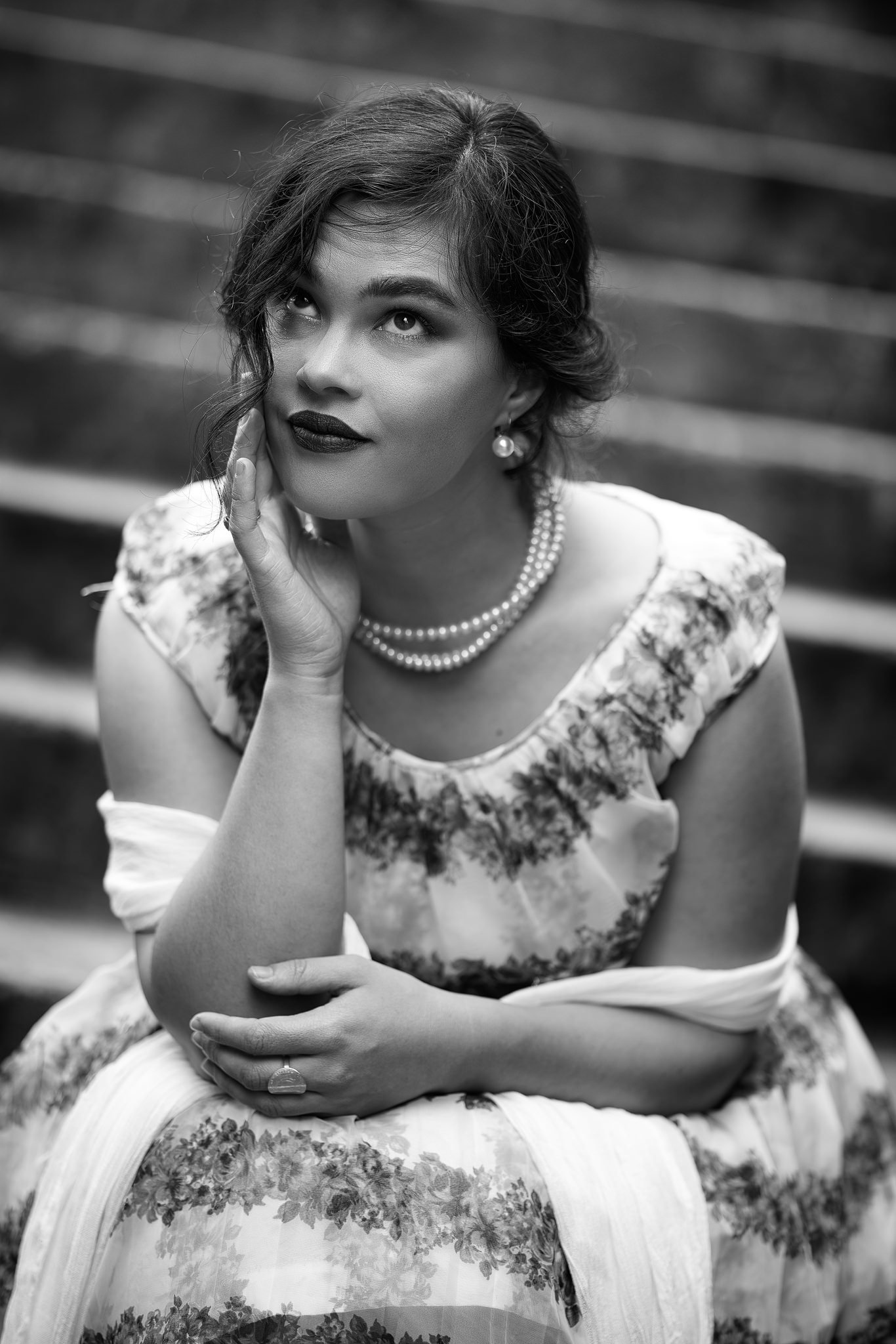 Black and white photo of Anita in a floral dress and pearls on steps