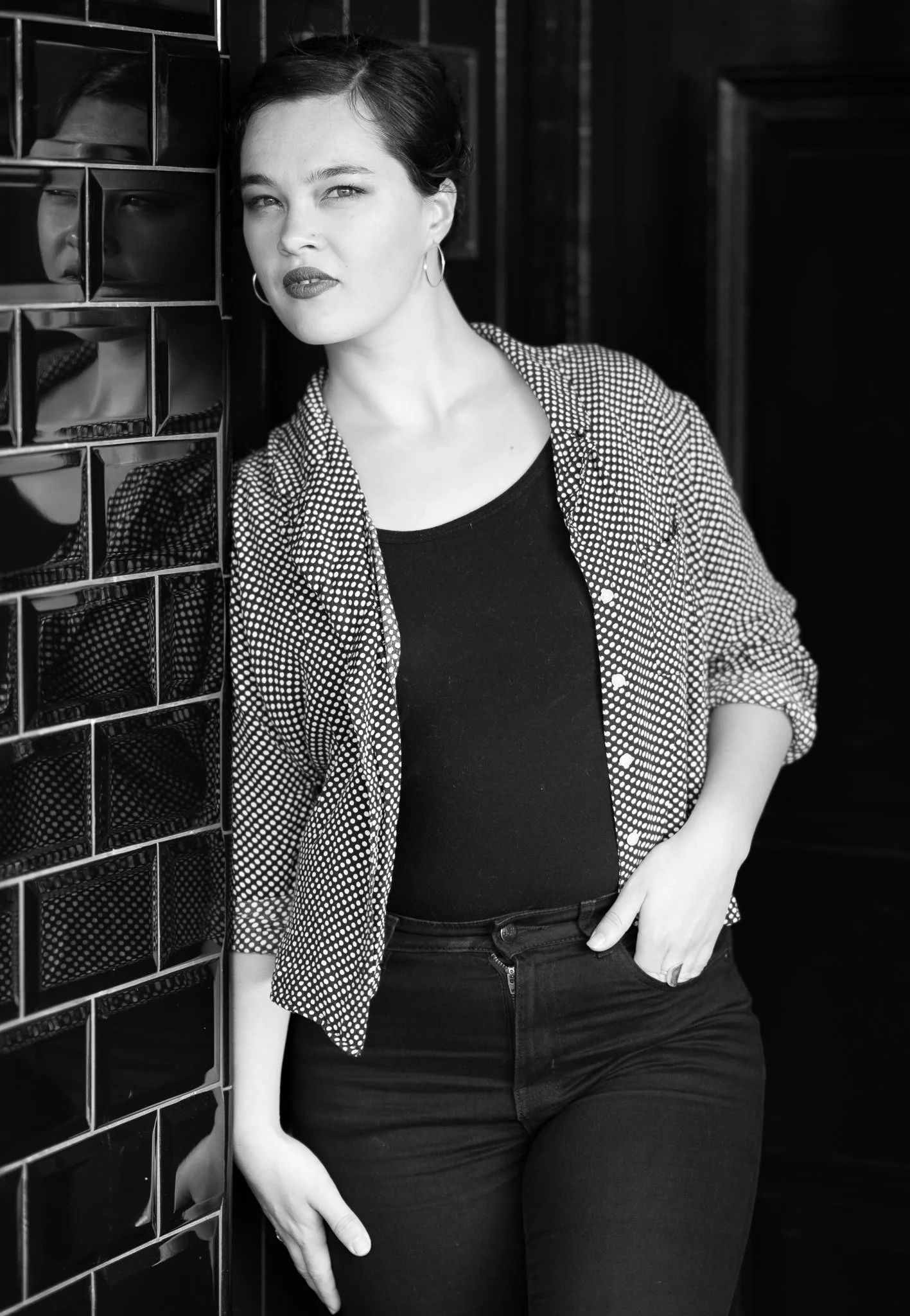 Black and white photo of Anita leaning against a tiled wall