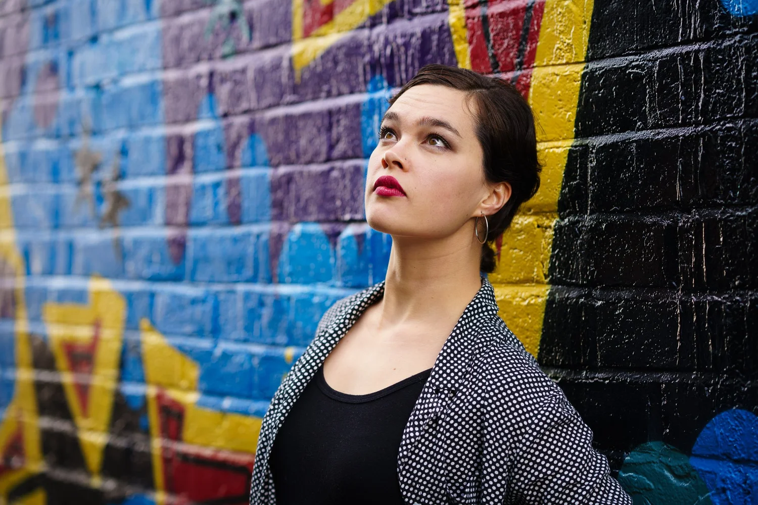 Anita poses in front of a colourful graffiti wall