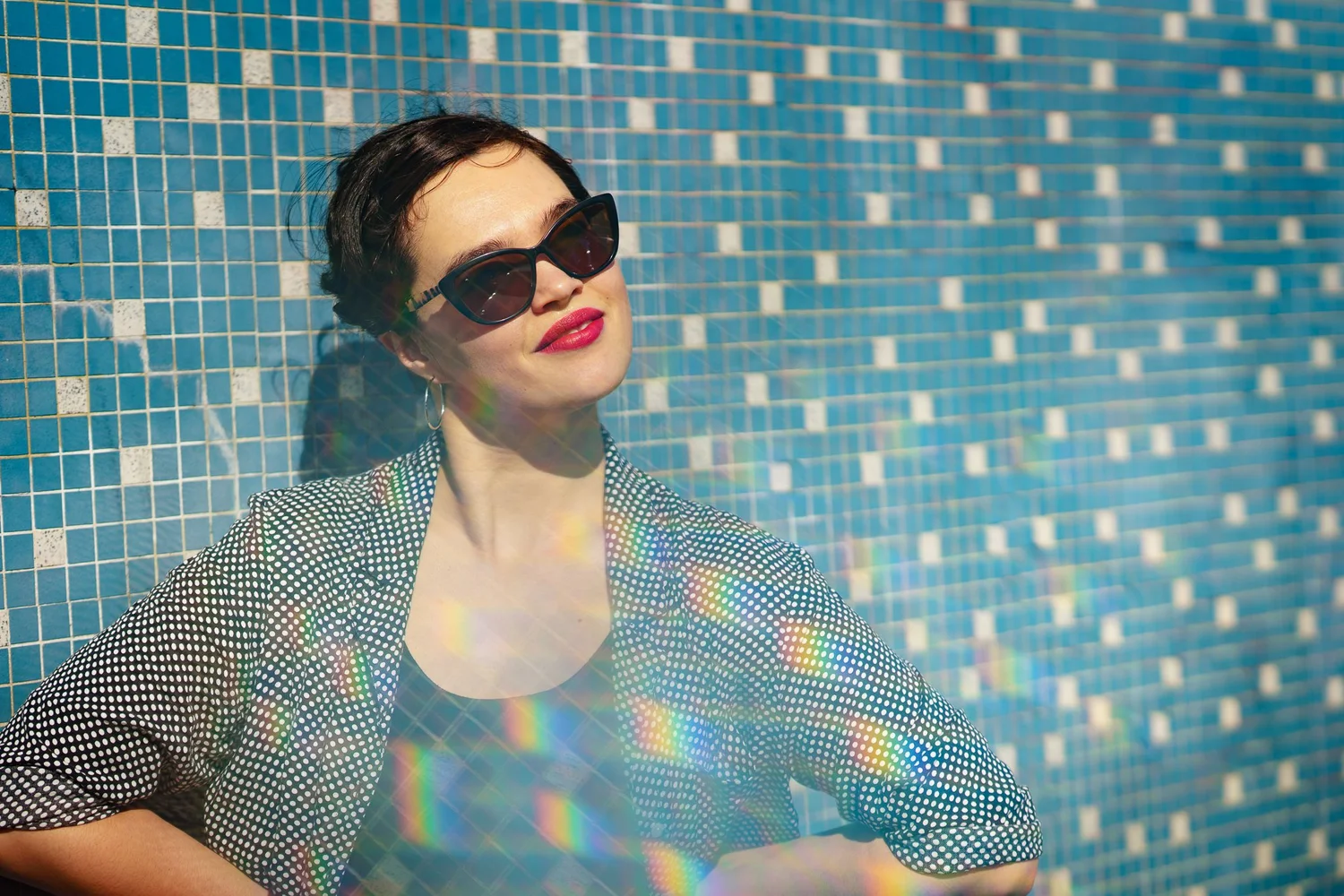Anita in sunglasses against a blue mosaic tile wall