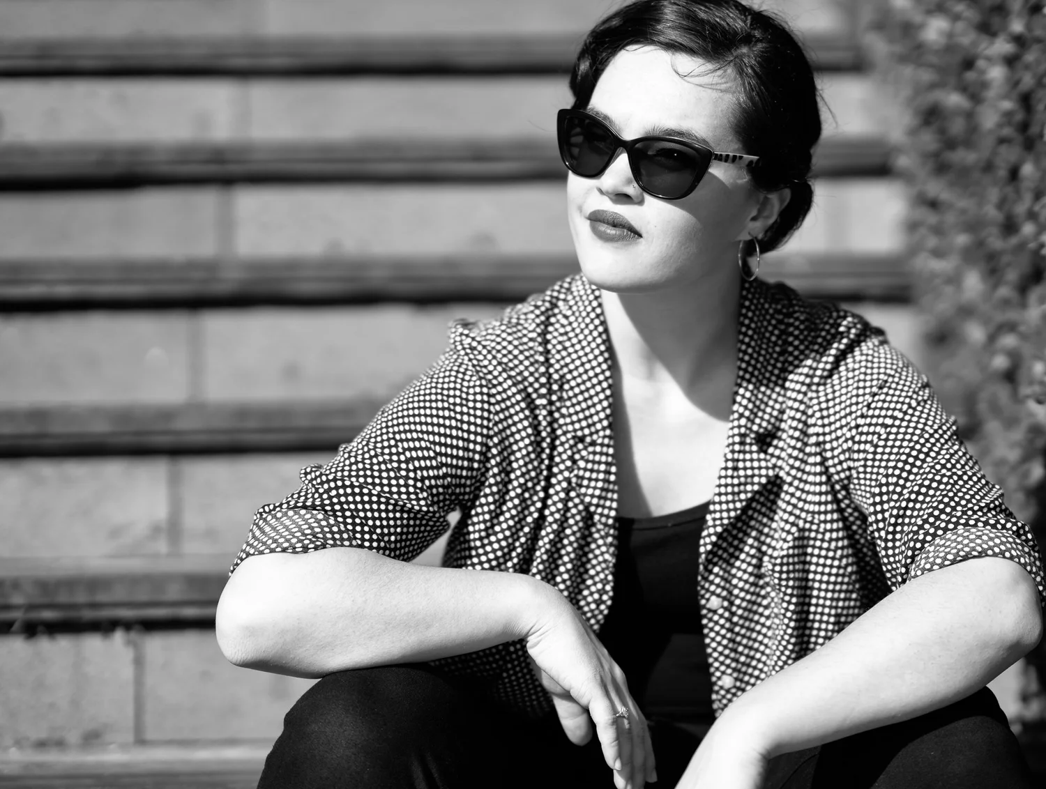 Black and white photo of Anita in sunglasses sitting on steps