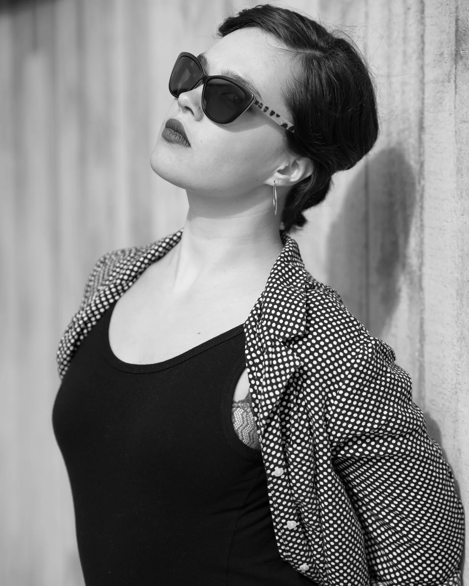 Black and white photo of Anita in sunglasses against a wall
