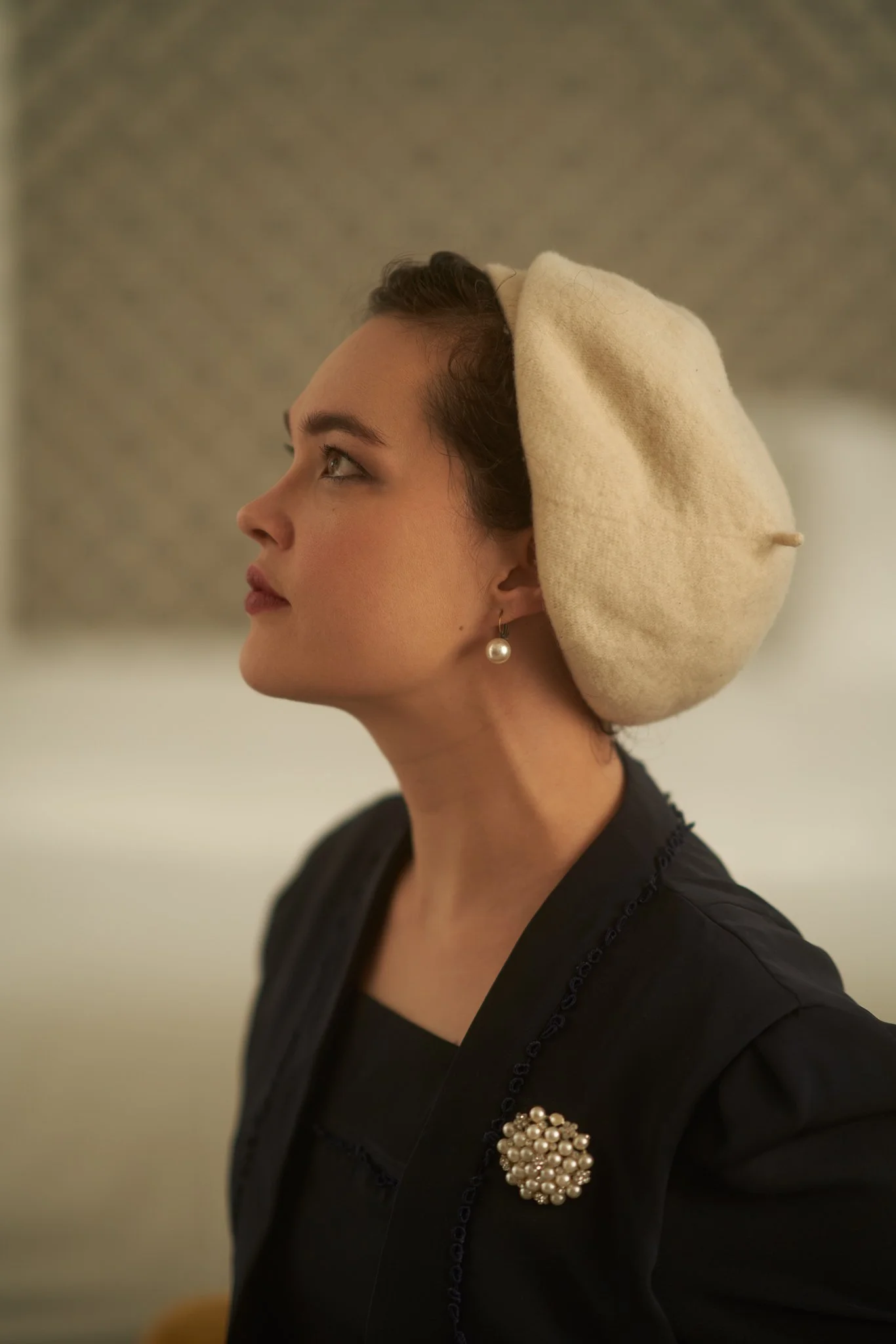 Anita in profile wearing a cream beret and black jacket
