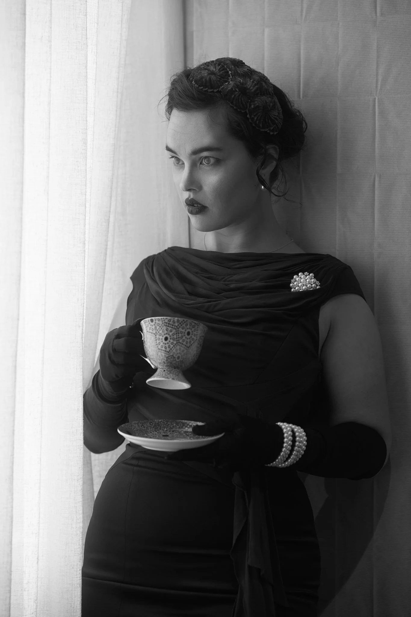 Black and white photo of Anita holding a teacup by a window