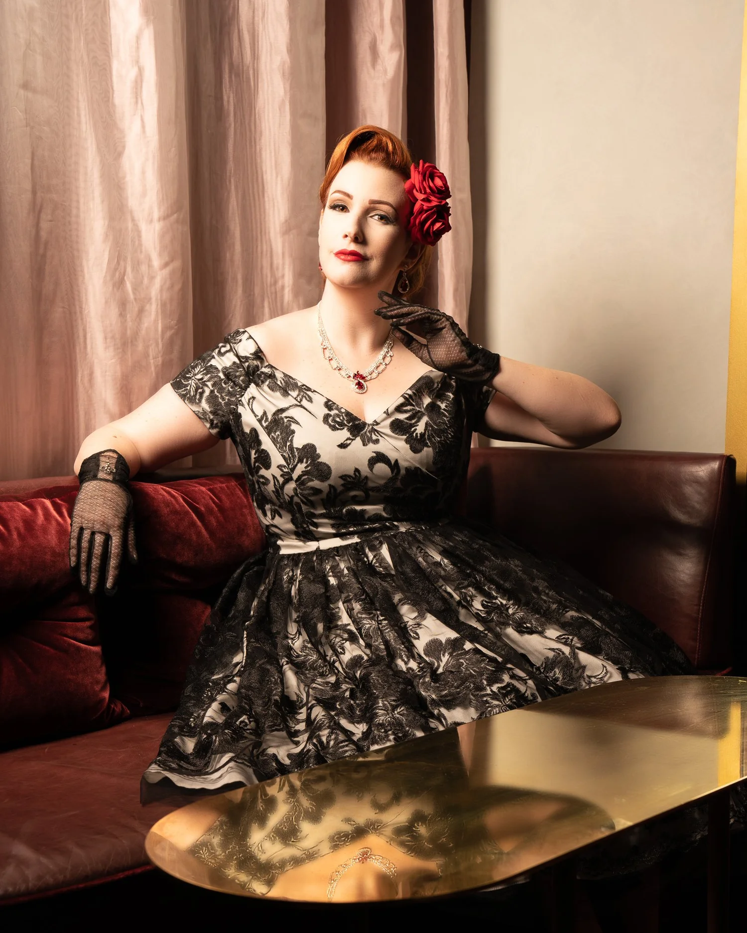 Jasmine leans back in a vintage booth beside a brass table