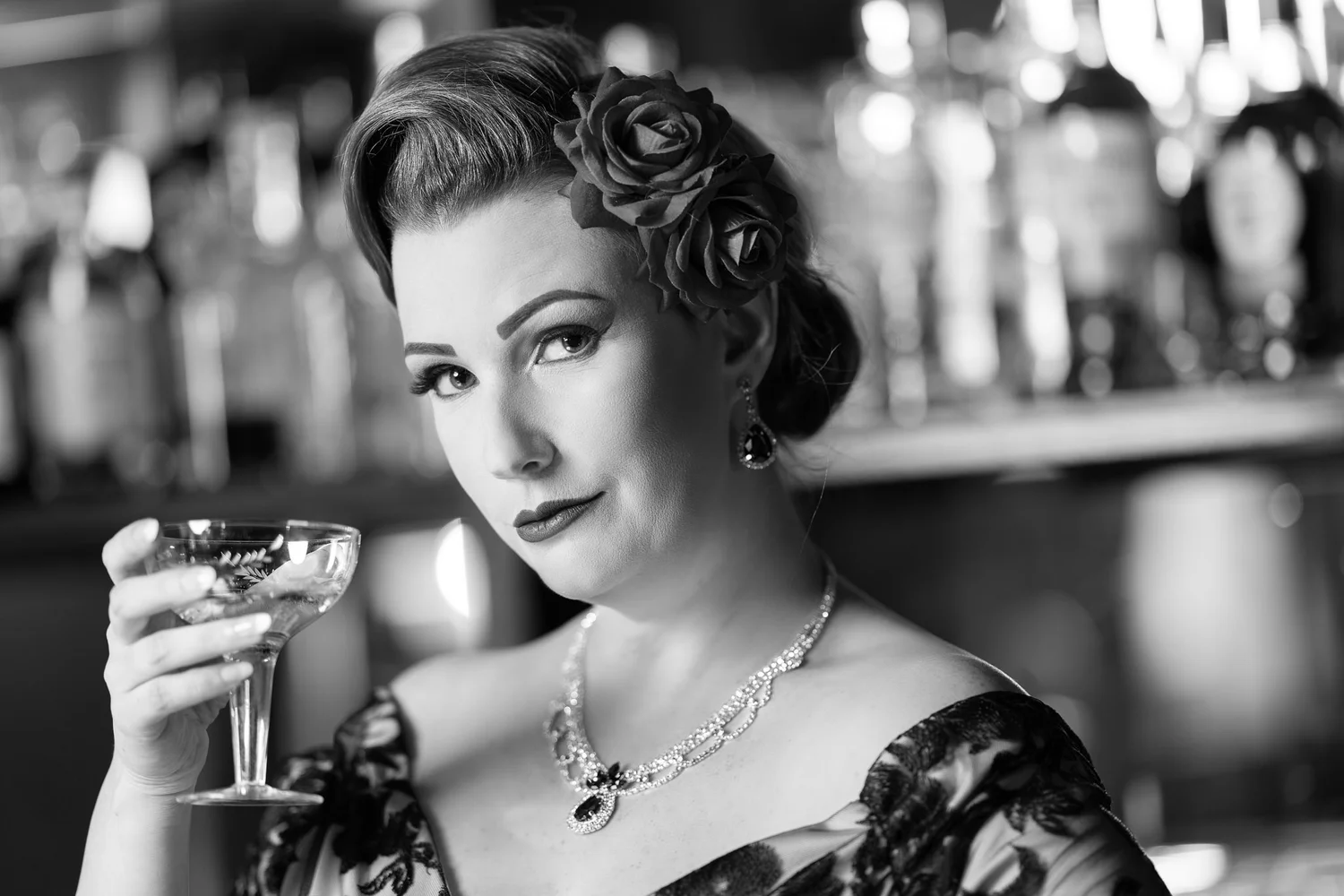 Black and white photo of Jasmine holding a coupe glass at the bar