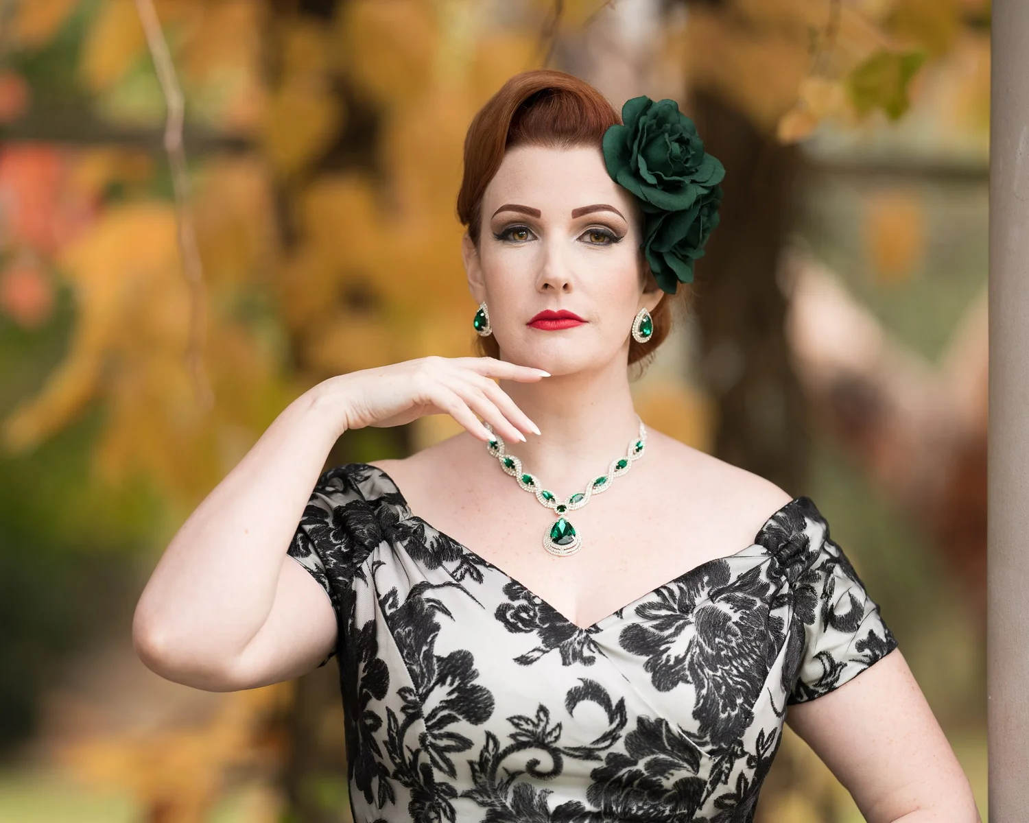 Jasmine in a lace dress with a green flower in her hair against autumn colours