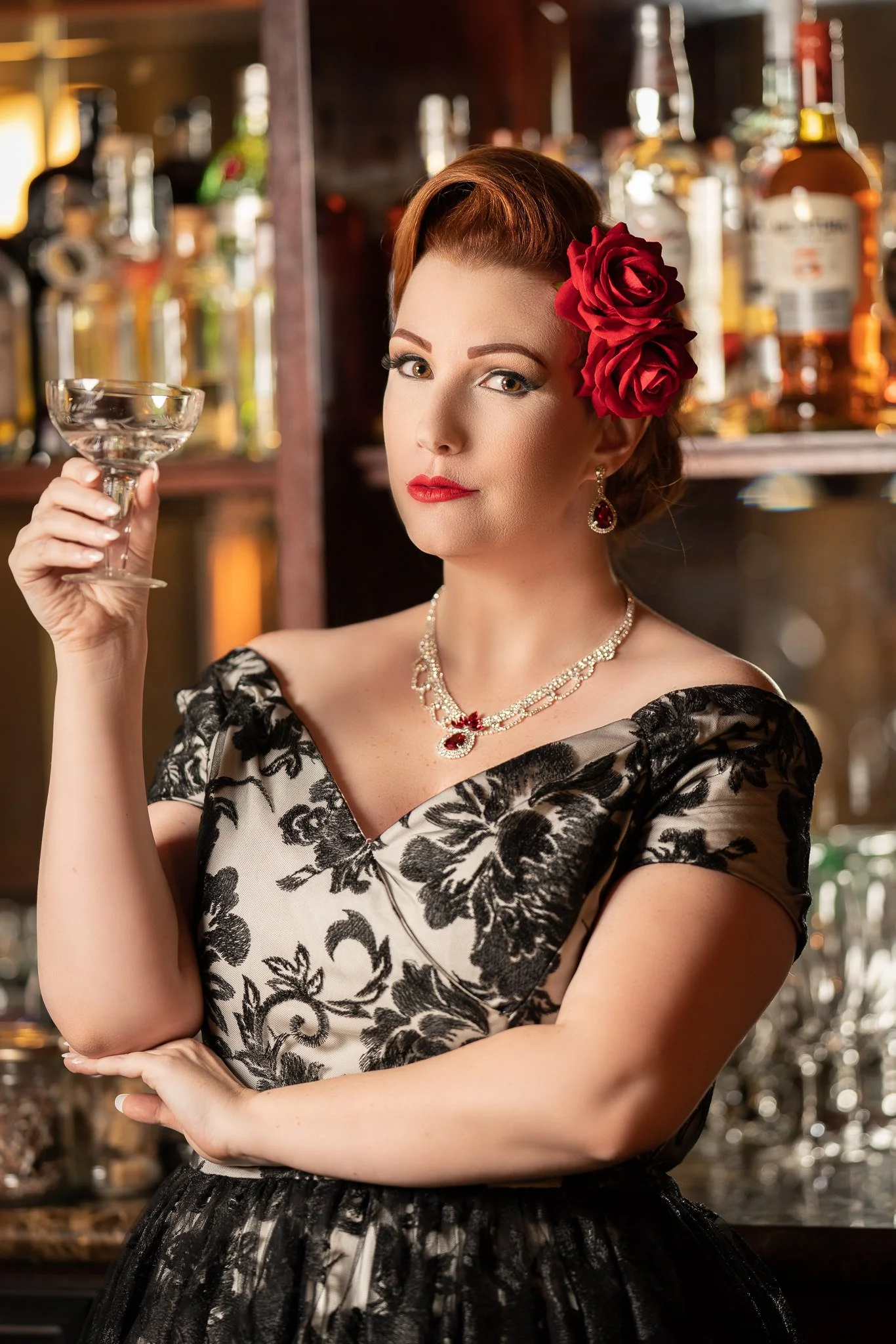 Jasmine leans on the bar holding a coupe glass