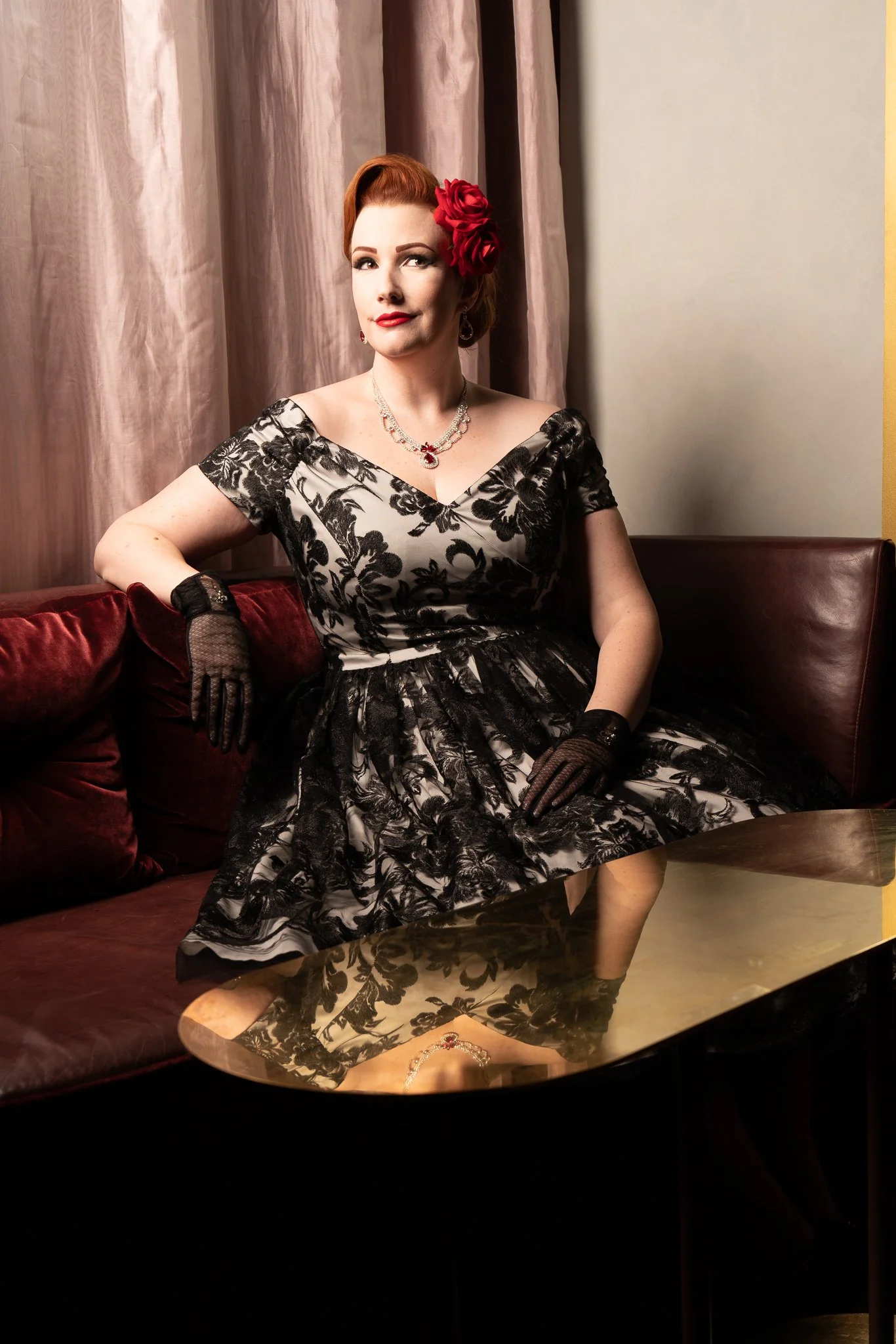 Jasmine poses in a vintage booth with a brass table in front
