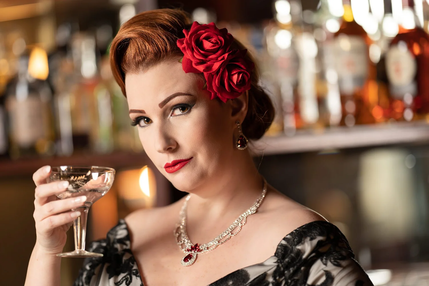 Jasmine smiles holding a coupe glass at the bar