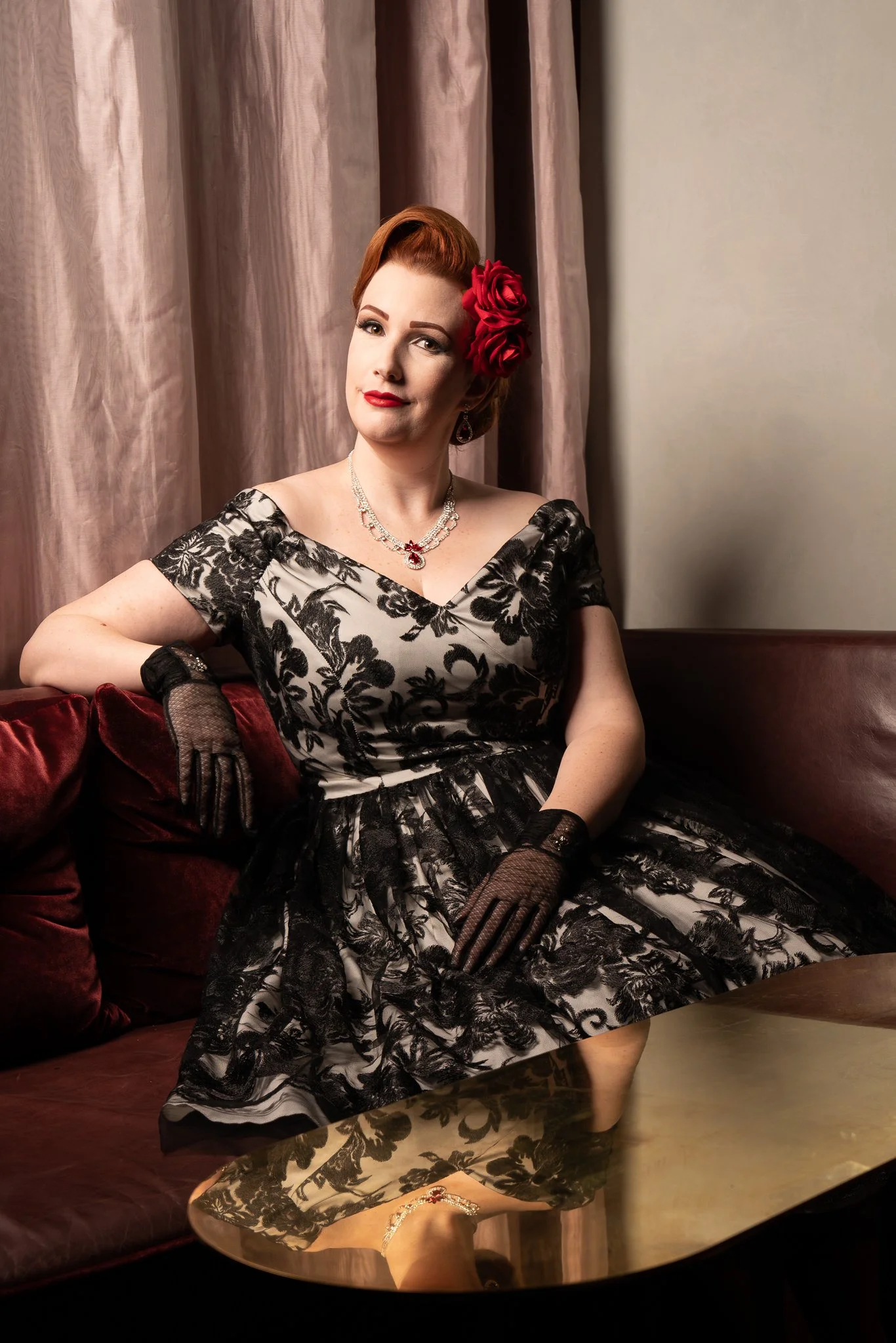 Jasmine seated in a vintage booth in black lace