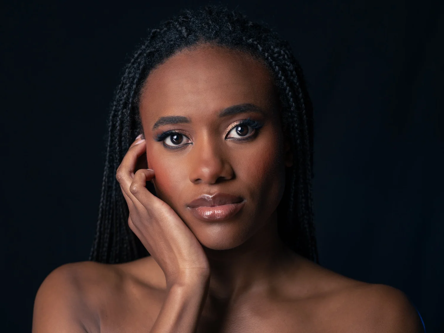 Ty rests her face on her hand in a studio portrait