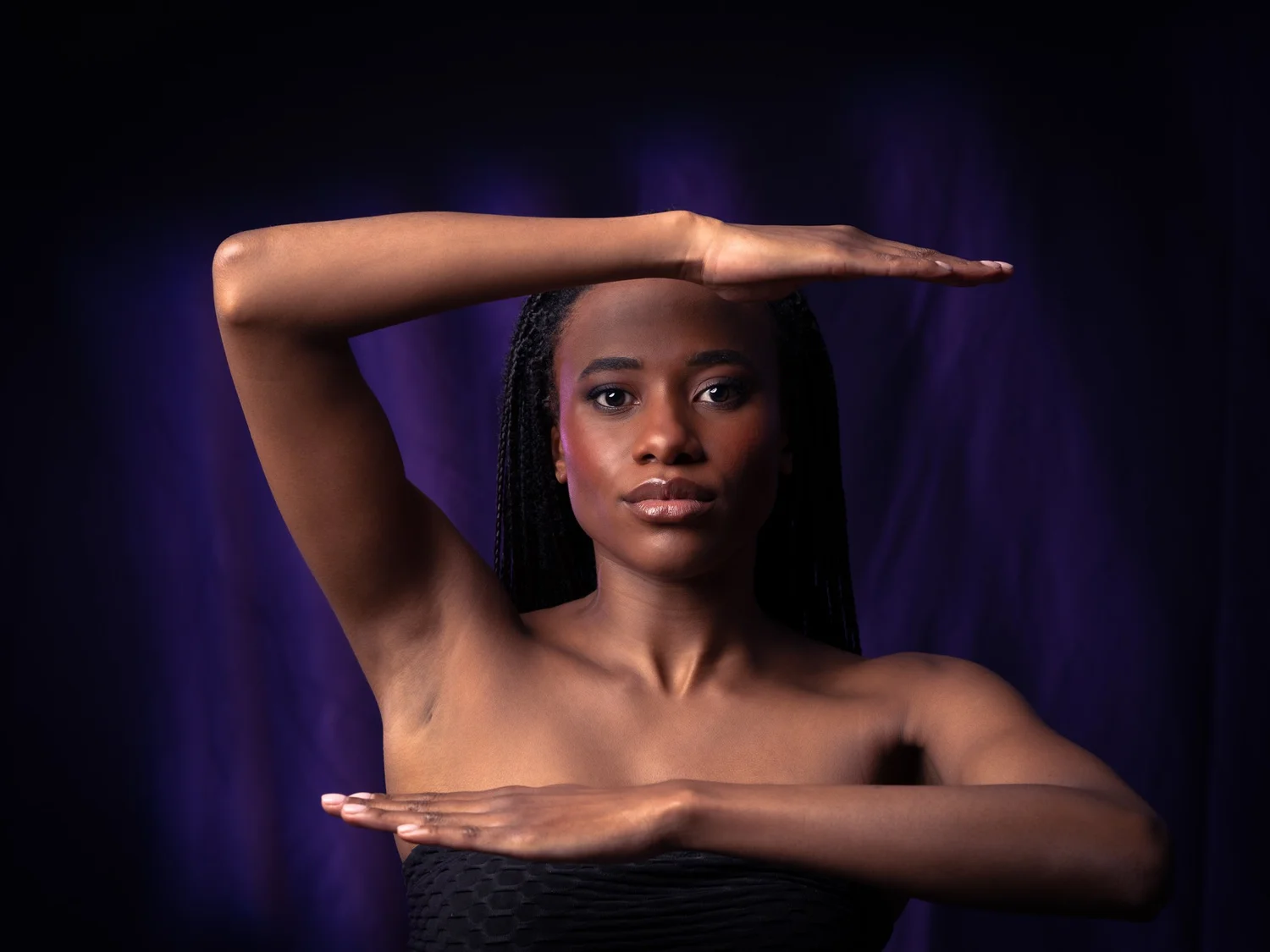 Ty frames her face with her arms against purple