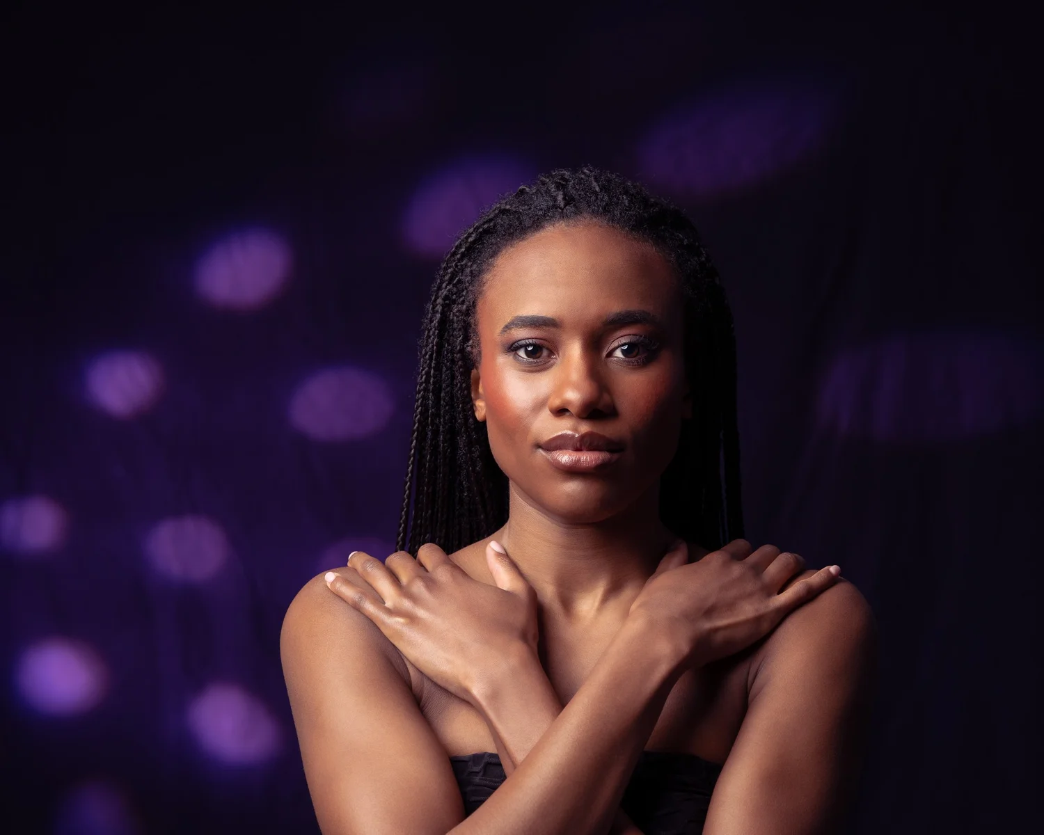 Ty with crossed arms against a purple patterned backdrop