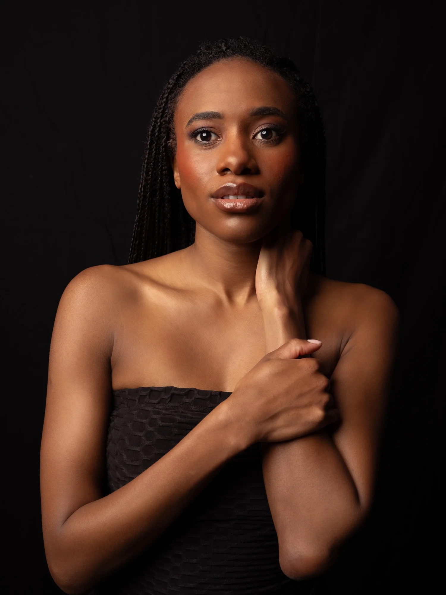 Ty with her hand at her neck against black