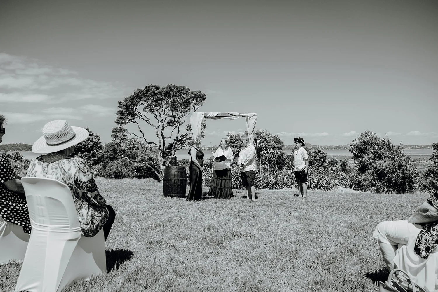 Black and white photo of the ceremony on the grass by the sea