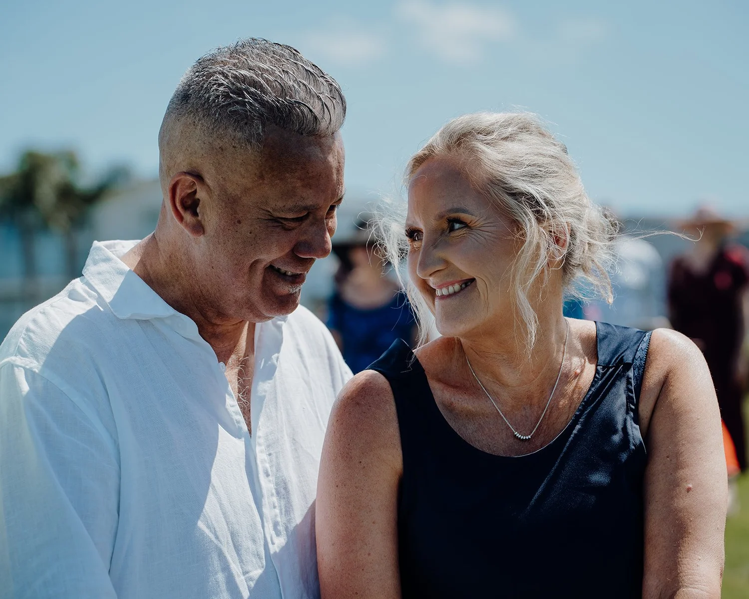 Raewyn and Shane smile at each other by the water