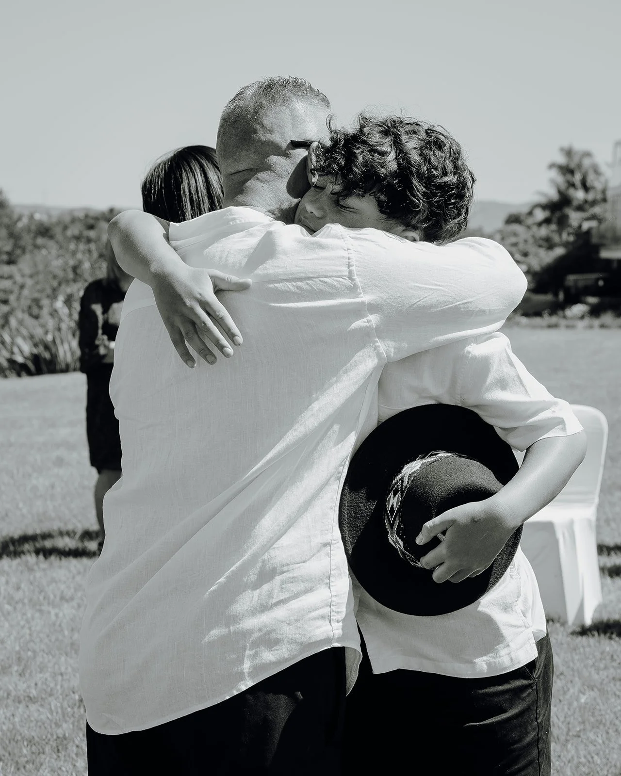 Black and white photo of Shane embracing a guest holding a hat