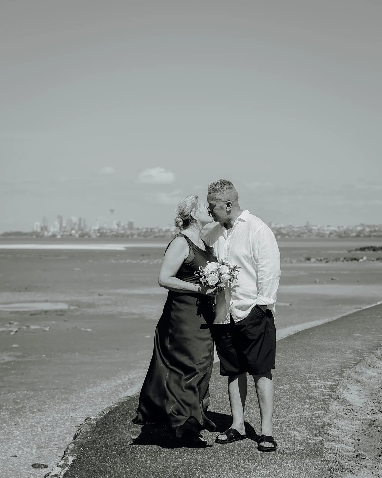 Black and white photo of Raewyn and Shane kissing on the beach