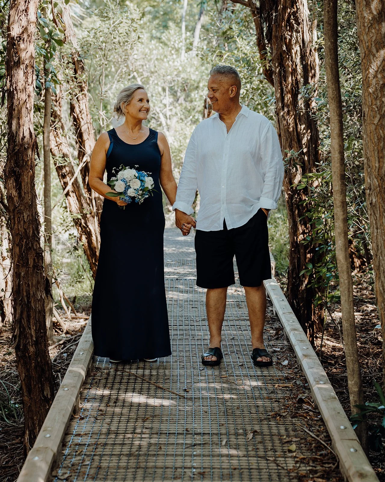Raewyn and Shane walk hand in hand along a bush boardwalk