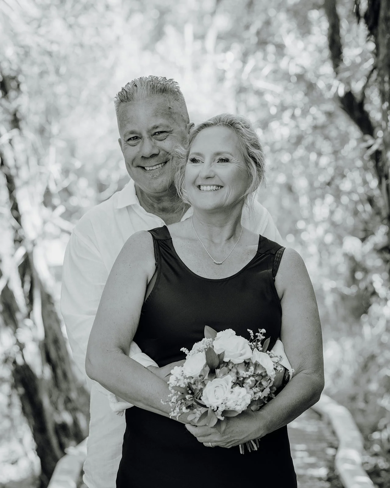 Black and white photo of Shane hugging Raewyn from behind