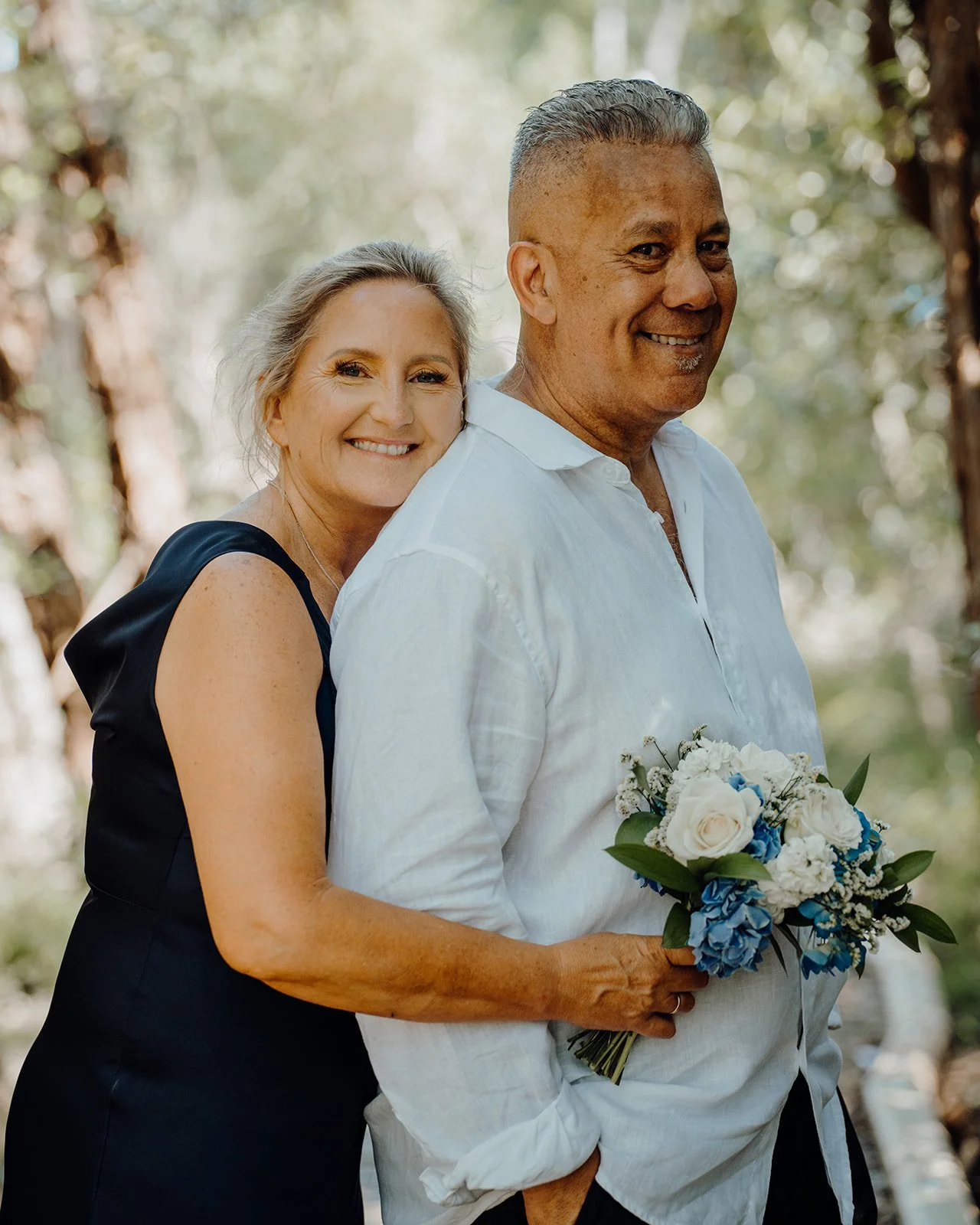 Shane hugs Raewyn holding her blue and white bouquet