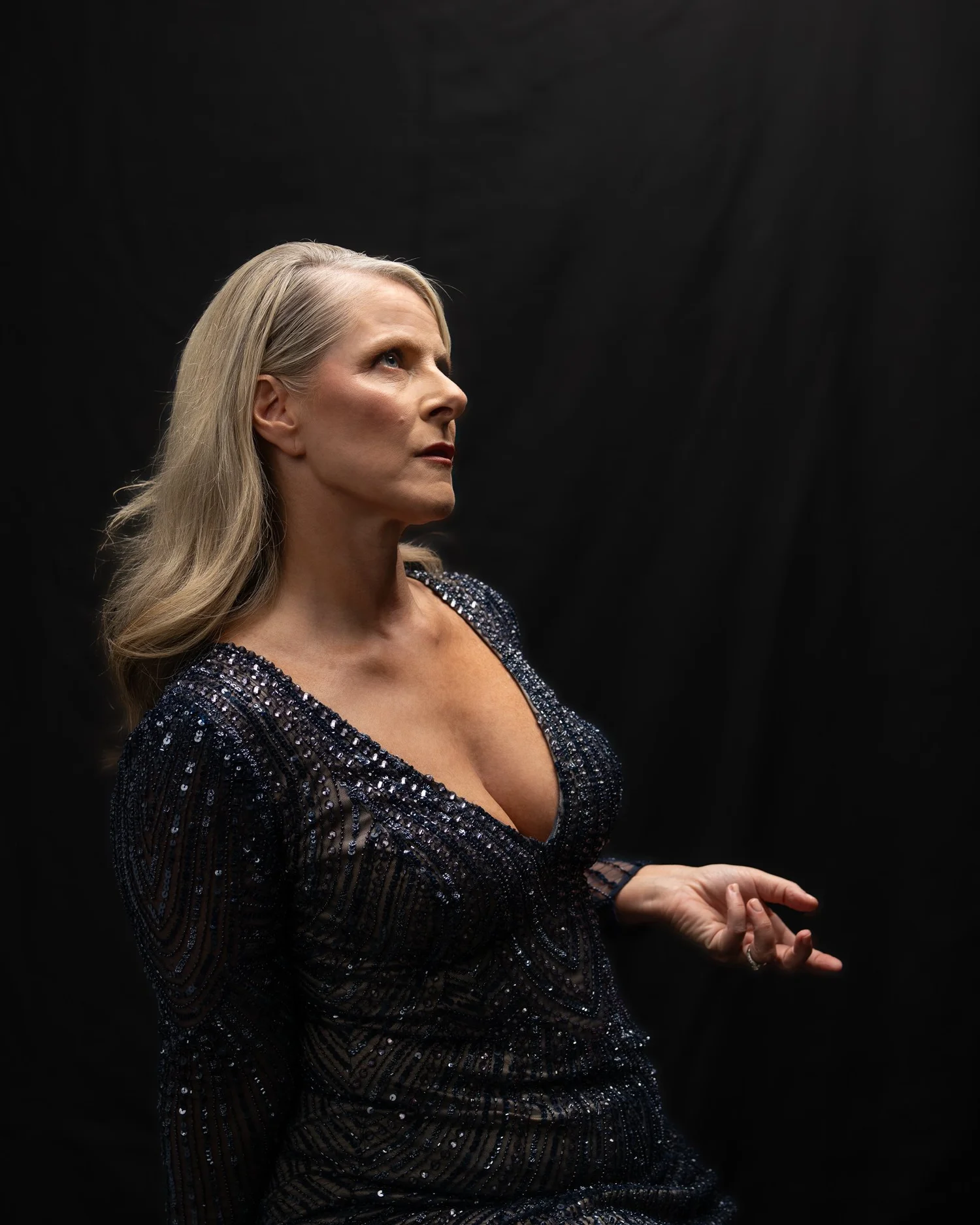 Ivanka in a sequinned gown gestures in dramatic side light