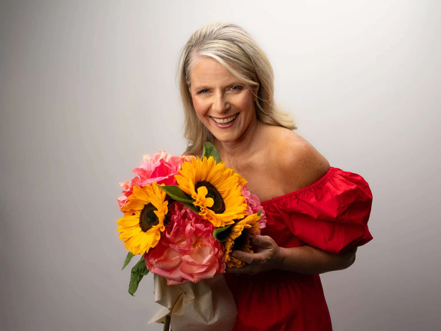 Ivanka in a red dress holding a bunch of sunflowers