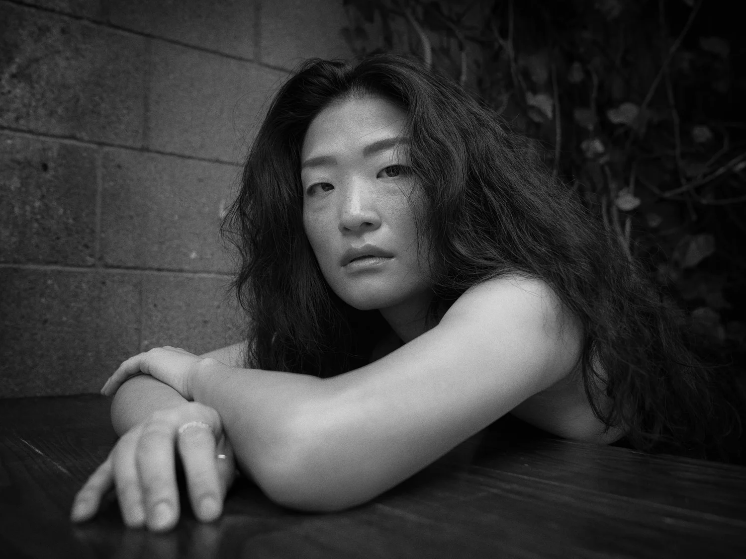 Black and white photo of Anna leaning on a table with her chin on her arm